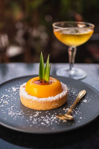 passion fruit dessert served at sunset next to a glass of champagne on a black plate