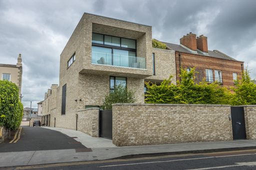 A view of Dublin city street side residential buildings with trees under the cloudy sky