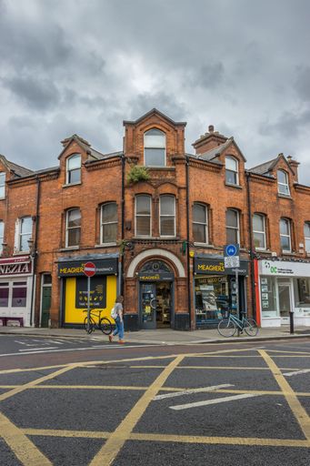 The vertical view of Dublin city street side corner building with shops under the cloudy sky