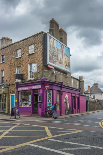 The vertical view of Dublin city street side buildings with shops under the cloudy sky