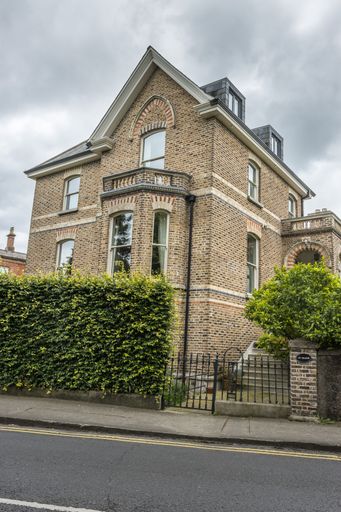 The vertical view of a street-side building with vintage brick facades under the cloudy sky in Dublin