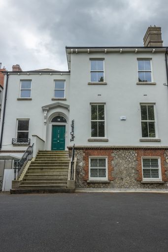 The vertical view of a street-side building with white facades under the cloudy sky in Dublin