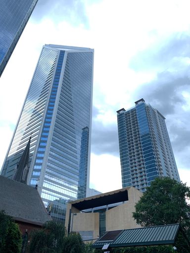 A vertical low angle shot of modern skyscrapers against blue coudy sky background