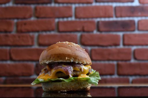 A closeup shot of a delicious hamburger against a brick wall