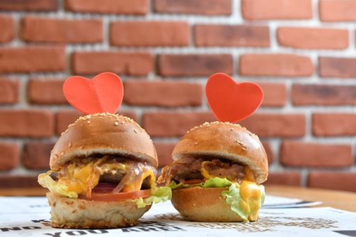 A closeup shot of two hamburgers with heart notes