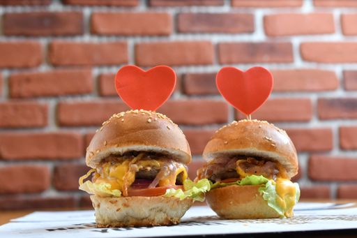 A closeup shot of delicious hamburgers with red heart notes against a brick wall
