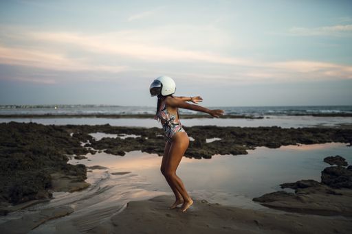 A young female in a swimsuit with a helmet preparing to jump at the Chiclana beach in Spain