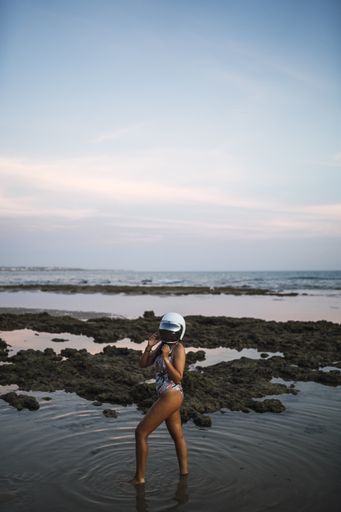 A vertical shot of a female in a swimsuit posing with a helmet in the sea in Cadiz, Spain