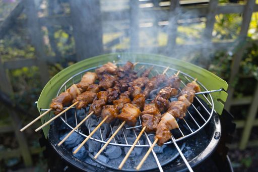 A pork barbecue on sticks on a small outdoor grill station