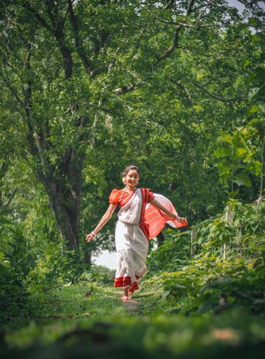 A vertical shot of a Bangladeshi girl jumping while wearing a traditional dress