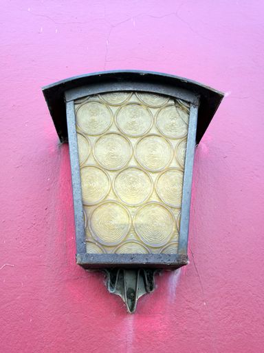 A vertical shot of a wall lamp on a pink wall