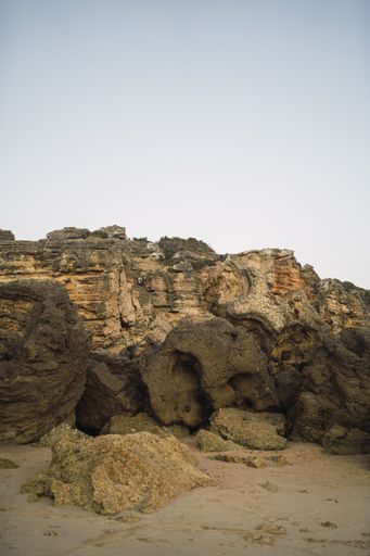 A vertical shot of rock formations on the beach under the sunlight in Cala Roche, Spain