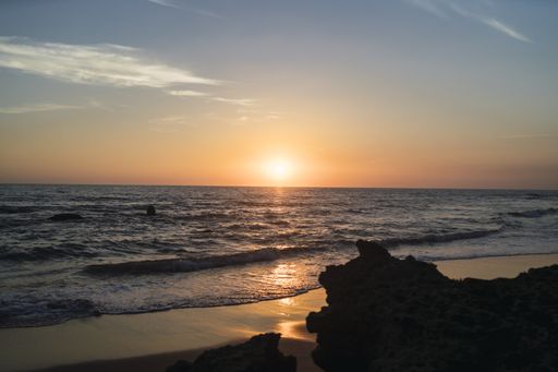 A landscape of the sea surrounded by the beach and rocks during the sunset in Cala de Roche, Spain
