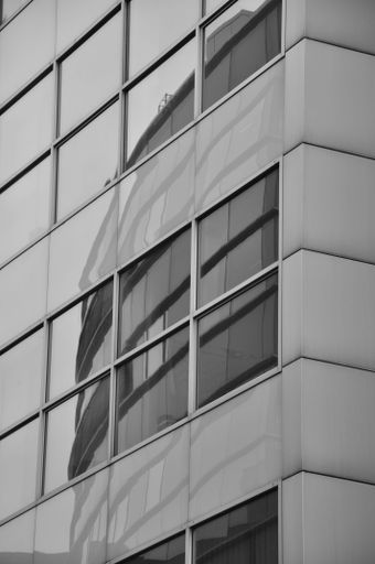 A vertical grayscale shot of buildings reflection in window pane in Media Harbor. Dusseldorf, Germany.