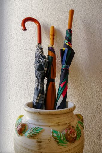 Three colorful stick umbrellas in a decorative vase