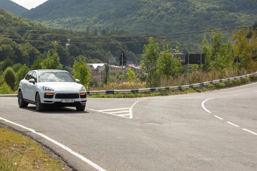 The Porsche Cayenne white car on the road surrounded by forest in Yerevan, Armenia