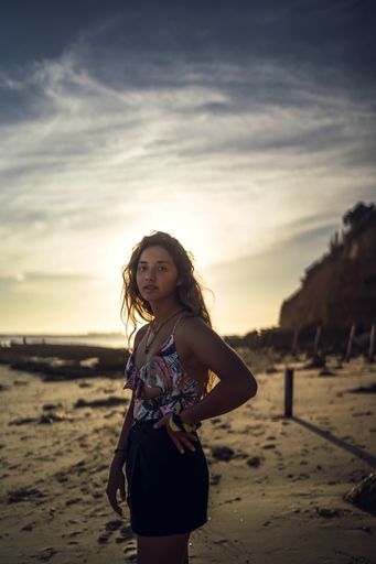 A vertical shot of a young female in swimsuit on background of seashore sunset