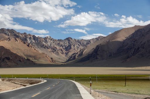 An aerial view of road through desert surrounded by hills