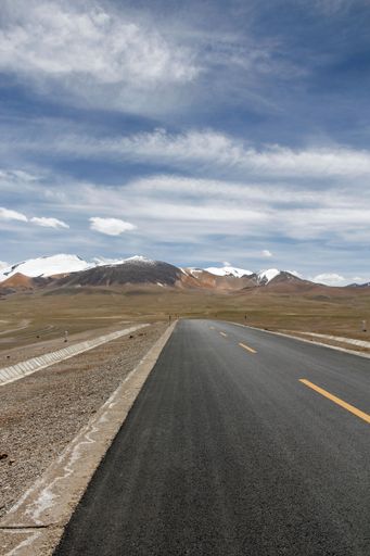 An aerial view of road through desert surrounded by hills