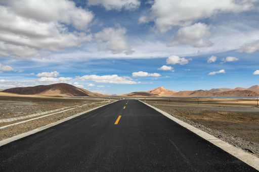 An aerial view of road through desert surrounded by hills