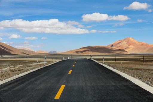 An aerial view of road through desert surrounded by hills