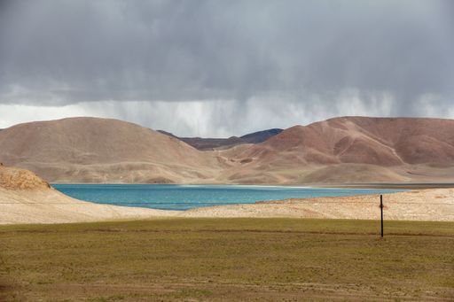 A landscape with a lake and mountains against the moody sky