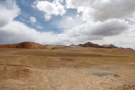 A landscape with a mountain range against the blue sky with floating clouds