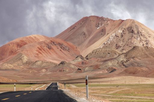 A landscape with a road and mountains against the sky with floating fog clouds