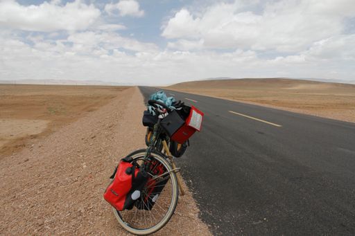 A bike on road through desert surrounded by mountains