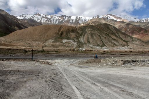 A landscape with a road and mountains against the sky with floating clouds