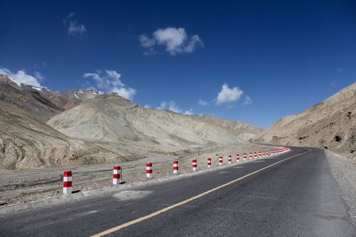 A landscape with a road and mountains against the sky with floating clouds