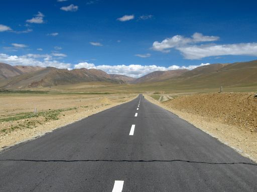 A beautiful shot of a road in a brown landscape under the clouds