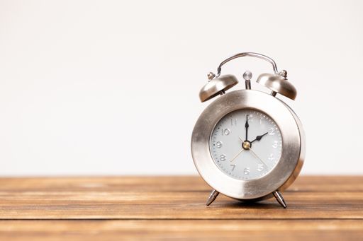 A closeup shot of an alarm clock placed on a wooden table
