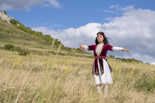 A shallow focus of a young female wearing a Bashkir traditional costume and dancing in a field