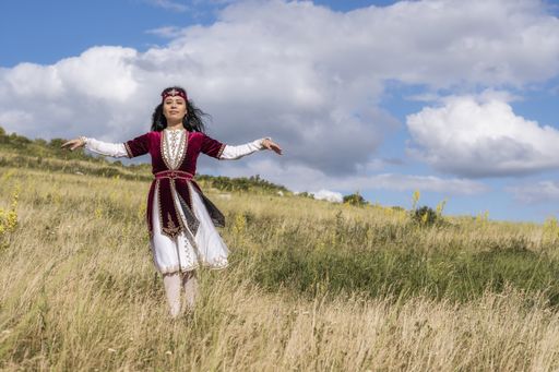 A young girl dancing a national dance in an open field