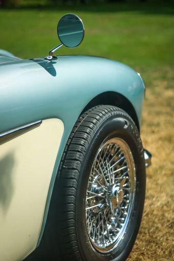 A vertical shot of the side of a vintage blue car with silver wheels