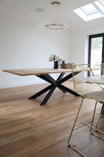 A vertical shot of a modern wooden table with flowers in the room. Interior design.