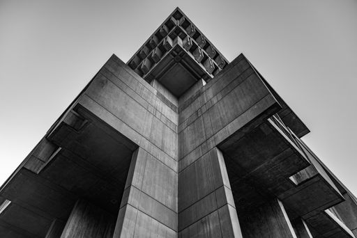A low angle greyscale shot of a concrete architectural structure under the clear sky