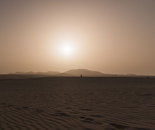 A low angle shot of a male walking in Dunes of Corralejo in the Canary Islands, Spain