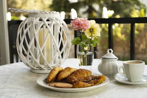 A closeup of a cup of coffee and a plate full of delicious pastries on a decorated table on a balcony