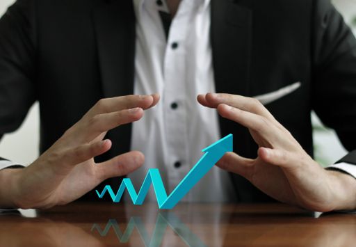 A businessman's hands over a growing graph arrow icon