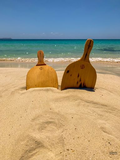 A vertical shot of wooden table tennis rackets in the sand on the beach in sunny weather