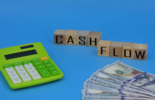 A layout of calculator, fake money and wooden cube with text "CASH FLOW"
