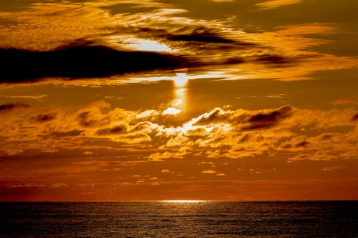 Golden sunset in a sky full of clouds over the Black sea - view from a beach in Batumi