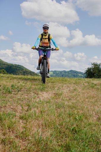 The vertical view of a boy riding the bicycle in the grass field on a sunny day