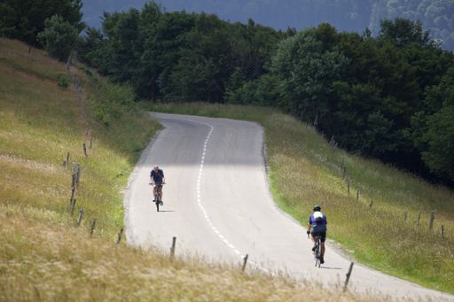 Two people riding bicycles on a curvy asphalt road during the daytime