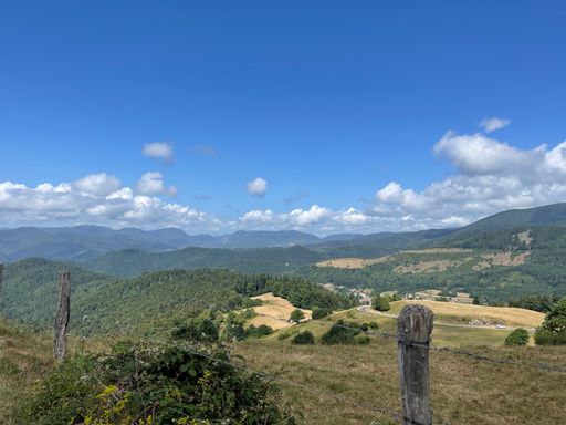 A beautiful natural scenery of green hills covered with forests under a blue sky with clouds