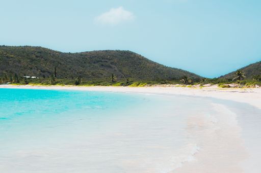 The beautiful Flamenco beach with forested hills and tropical trees on the sandy shore in Puerto Rico