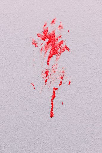 A vertical shot of a white grunge wall with red paint splashes