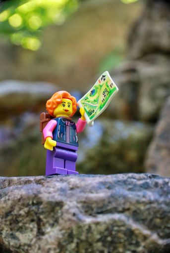 A closeup shot of a female hiki toy figure standing on a rock holding a map